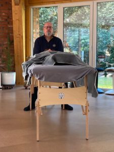 Thomas Gerding bei einer Craniosacralen Begleitung, sitzend an einer Liege